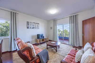 a living room with a couch and a table andwindows at Vivenda Paz Lobo by YOUR KEY MADEIRA in Gaula