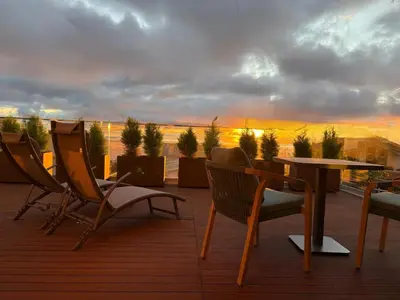 a deck with chairs and a table and a sunset at BHF Residences Luxe Sunset in Arco da Calheta