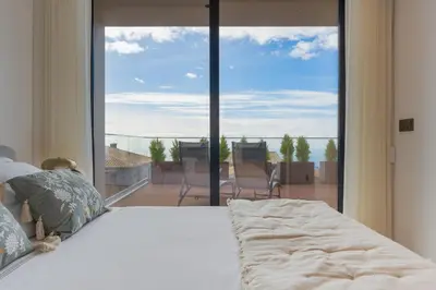 a bedroom with a bed and a large window at BHF Residences Luxe Sunset in Arco da Calheta