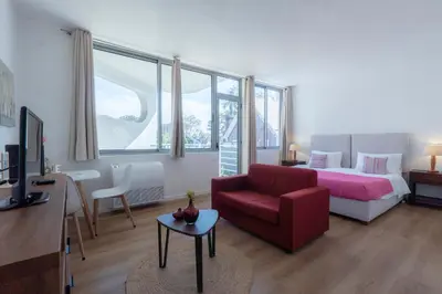 a living room with a bed and a red chair at Apartamento Navio Azul in Funchal