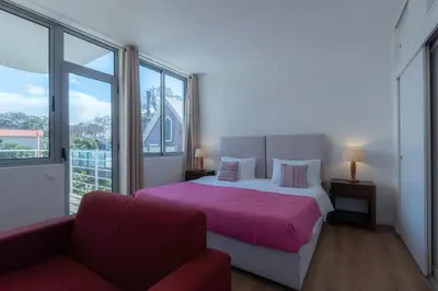 a bedroom with a bed and a couch and windows at Apartamento Navio Azul in Funchal
