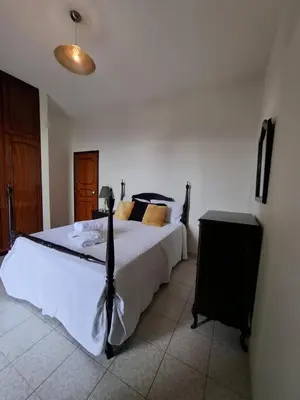 a bedroom with a large white bed with a wooden door at Rosolamar Villa with Ocean View in Câmara de Lobos