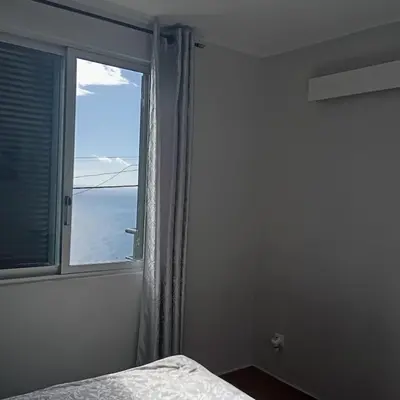 a bedroom with a window with a view of the ocean at Yellow owl in Campanário