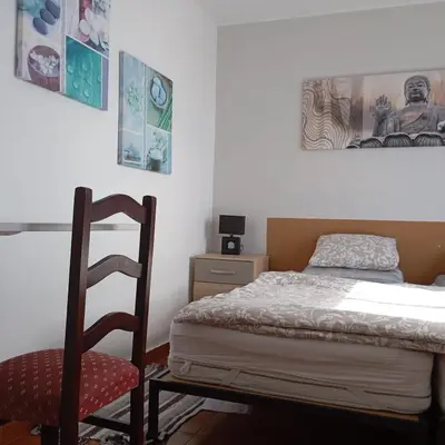 a small bedroom with a bed and a chair at Yellow owl in Campanário
