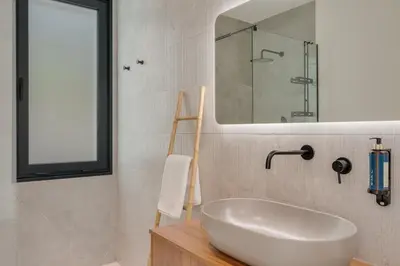 a bathroom with a white sink and a mirror at BHF Residences Luxe Family in Arco da Calheta