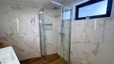 a bathroom with a shower with a television on the wall at Sophia House By Sam Houses in Canhas