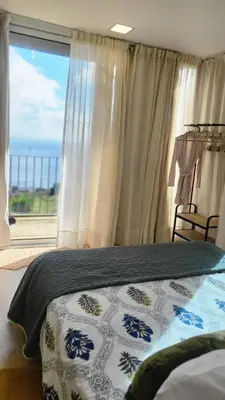 a bedroom with a bed and a large window at Personal blue house Madeira in Santa Cruz