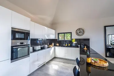 a kitchen with white cabinets and a table in it at Passaras - countryside retreat in west of island in Ponta do Pargo
