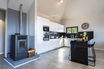 a large kitchen with white cabinets and a clock on the wall at Passaras - countryside retreat in west of island in Ponta do Pargo