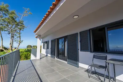 a balcony of a house with a table and chairs at Passaras - countryside retreat in west of island in Ponta do Pargo