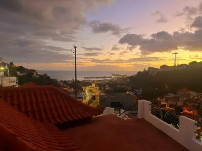 a view of a city at sunset from a rooftop at Funchal Pink Hostel in Funchal