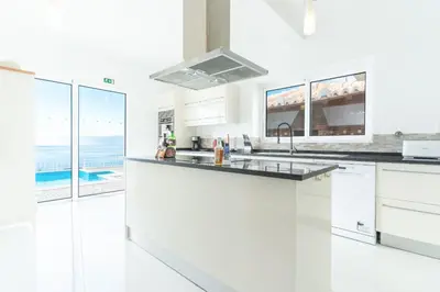a white kitchen with a view of the ocean at Villa Valentina by Atlantic Holiday in Ponta do Sol