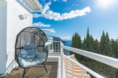 a wicker chair on a balcony with a view of the ocean at Villa Valentina by Atlantic Holiday in Ponta do Sol
