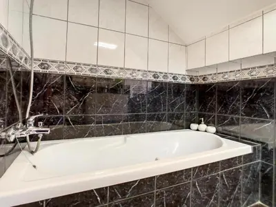 a white bath tub in a black tiled bathroom at Villa Baradaye by Atlantic Holiday in Estreito da Calheta
