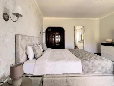 a bedroom with a large white bed and a table at Villa Baradaye by Atlantic Holiday in Estreito da Calheta