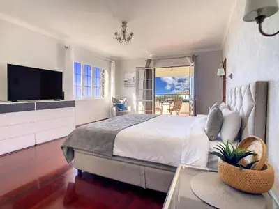 a bedroom with a large bed and a television at Villa Baradaye by Atlantic Holiday in Estreito da Calheta
