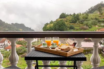 a tray of food on a balcony with glasses of orange juice at View to the Valley, By OP in Senhora do Rosário