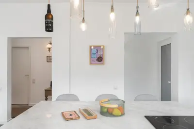 a white kitchen with a table with a bowl of fruit at Casa da Anoneira House with Pool and Sea View in Funchal