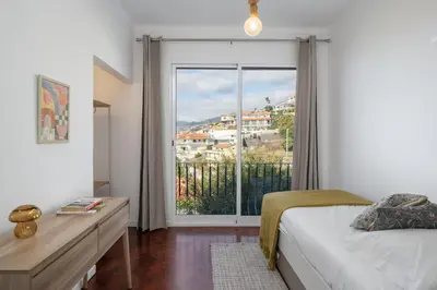 a bedroom with a bed and a large window at Casa da Anoneira House with Pool and Sea View in Funchal
