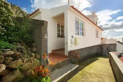 a white house with a stone wall at Sunset Cliffs By Slice Of Heaven in Ribeira Brava