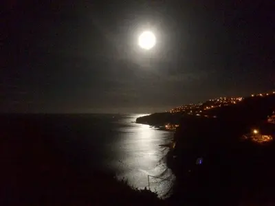 a full moon rising over the ocean at night at Sunset Cliffs By Slice Of Heaven in Ribeira Brava