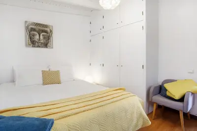a white bedroom with a bed and a chair at Sunset Cliffs By Slice Of Heaven in Ribeira Brava