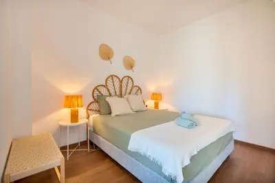 a bedroom with a bed with two lamps on it at Tenório Beach Apartment in Lagos