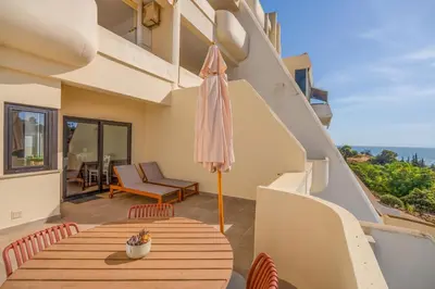 a white living room with a tv and a couch at Tenório Beach Apartment in Lagos