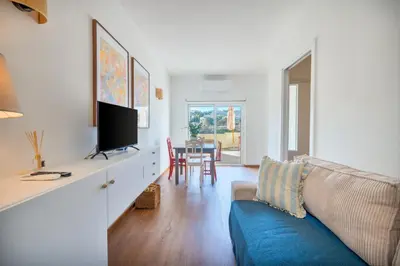 a living room with a blue couch and a tv at Tenório Beach Apartment in Lagos