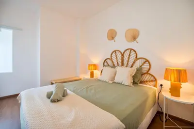 a bedroom with a large bed with two lamps and two tables at Tenório Beach Apartment in Lagos