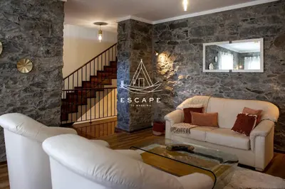 a living room with two white couches and a stone wall at Faias House by Escape to Madeira in Ribeira do Raposo