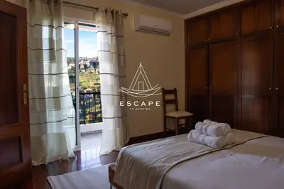 a bedroom with a bed and a large window at Faias House by Escape to Madeira in Ribeira do Raposo