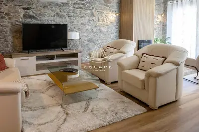a living room with two chairs and a television at Faias House by Escape to Madeira in Ribeira do Raposo