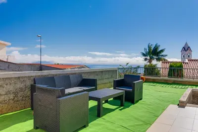 a patio with two chairs and a table on a roof at Andrade's Villa by Holiday Rental Madeira in Caniço
