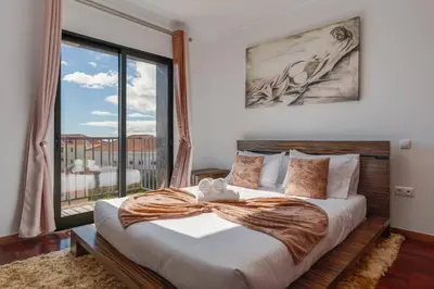 a bedroom with a large bed with a large window at Andrade's Villa by Holiday Rental Madeira in Caniço