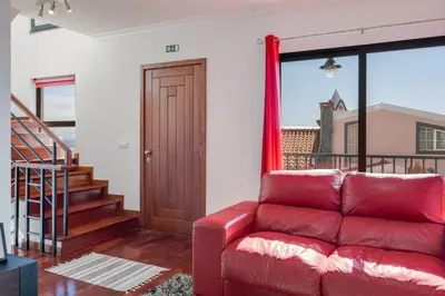 a red couch in a living room with a sliding glass door at Andrade's Villa by Holiday Rental Madeira in Caniço