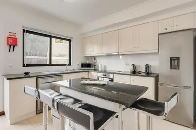 a kitchen with white cabinets and a black counter top at Andrade's Villa by Holiday Rental Madeira in Caniço