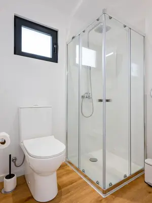 a bathroom with a toilet and a glass shower at The Village View I, By OP in São Vicente