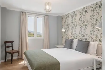 a bedroom with a bed and a chair and a window at Casas ao Sol by An Island Apart in Ponta do Sol