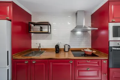 a red kitchen with red cabinets and a sink at Casas ao Sol by An Island Apart in Ponta do Sol