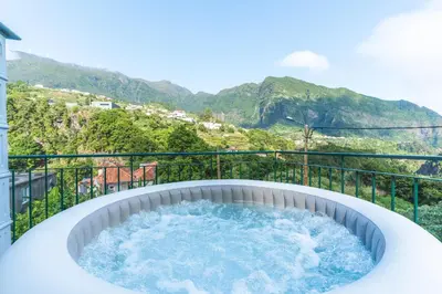 a hot tub on a balcony with mountains in the background at Villa Bella Vista by AH in São Vicente