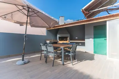 a patio with a table and chairs and an umbrella at Villa Bella Vista by AH in São Vicente