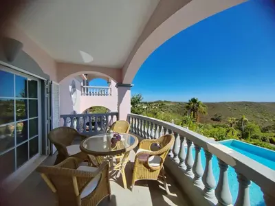 a balcony with a table and chairs and a pool at Private Bedroom in a Luxurious Villa, Budens in Budens