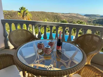 a glass table with two bottles of wine on a balcony at Private Bedroom in a Luxurious Villa, Budens in Budens