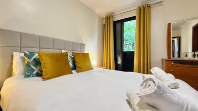 a bedroom with a large white bed with yellow curtains at Vista Pena in Funchal