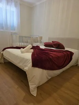 a large bed with red and white sheets and pillows at Pátio do Garajau in Caniço