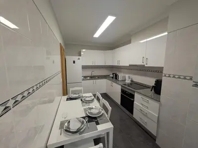 a large white kitchen with white cabinets and appliances at Pátio do Garajau in Caniço