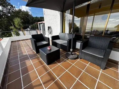 an outdoor patio with chairs and an umbrella at Machico View in Machico
