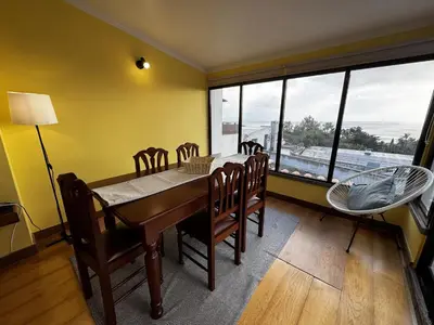 a dining room table with chairs and a large window at Machico View in Machico