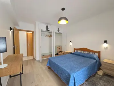 a bedroom with a blue bed and a table and a lamp at Cozy Airport Apartment in Machico